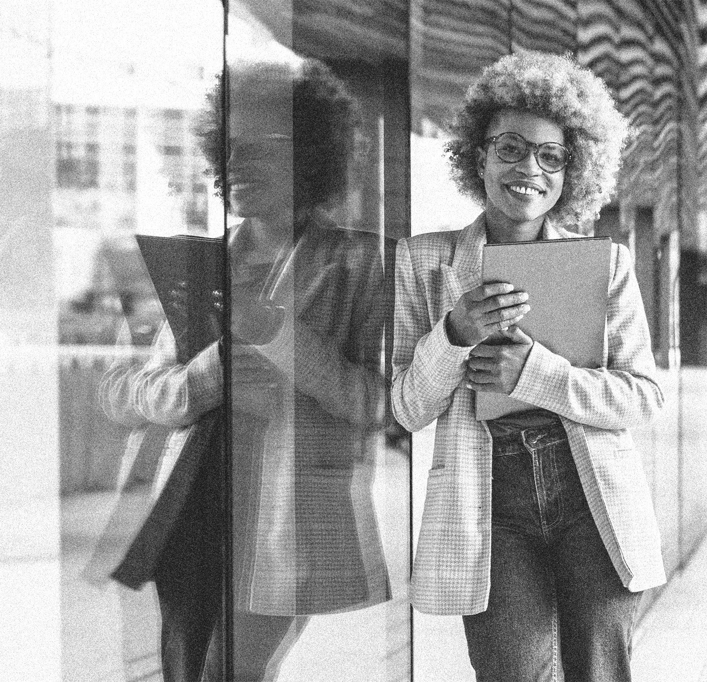 Confident executive woman holding her laptop posing outside an office building.