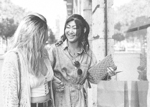 Two smiling female consumers walking outside of a store.