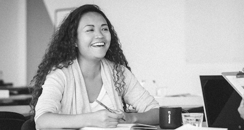 Woman smiling and holding a pencil.