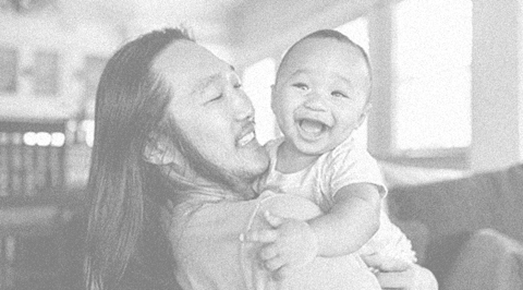 Asian dad holding his baby laughing