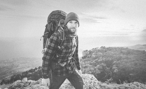 A man with backpack climbing a mountain.