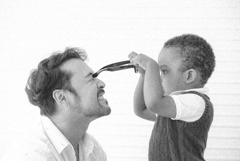 Toddler boy putting glasses on his dad.