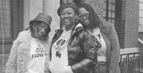 Three black women standing together smiling.