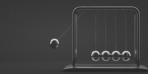 Close up of Newton’s cradle, an example of the momentum necessary for business transformation.