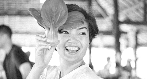 A women smiles and holds up a vegetable.