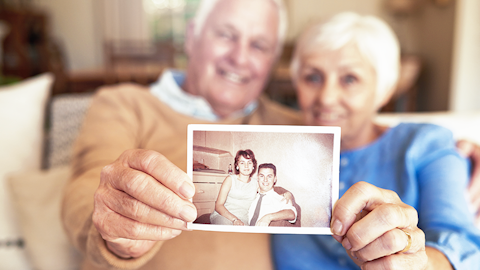 Elderly couple shows a younger photo of them when they first met to the camera.