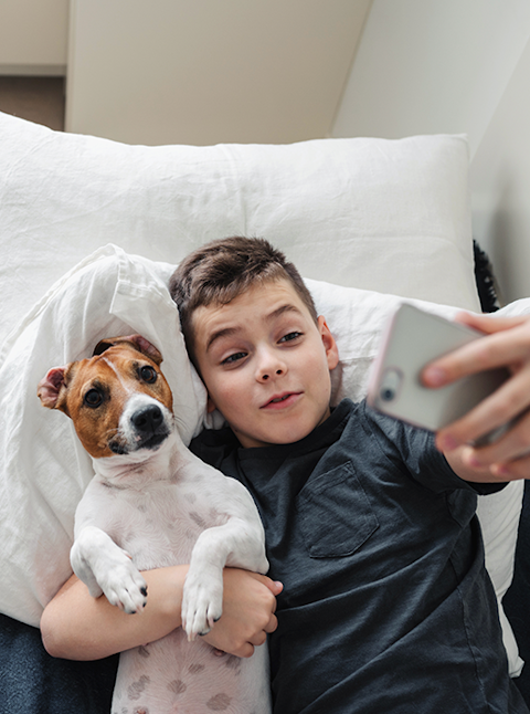 Young boy takes a selfie with the family dog.