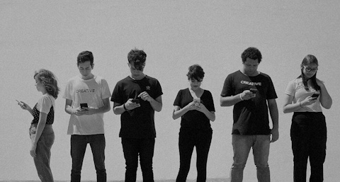 Group of people standing and looking at their phones.