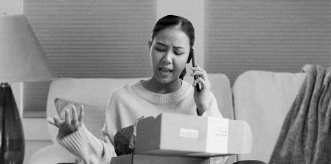 Frustrated woman on the phone after opening a package.