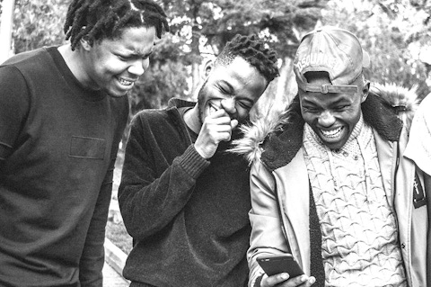 Group of young men looking at a phone and laughing.