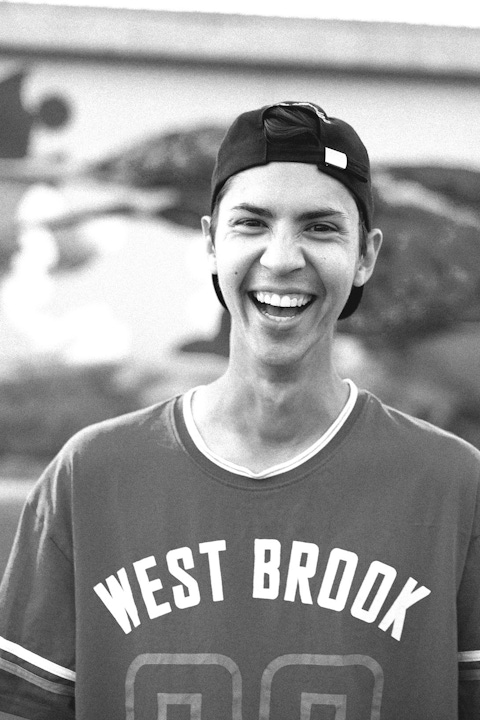 Smiling young man in a jersey and backwards baseball cap.