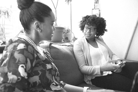 Two women discussing an ATU market research study on a couch in a conference room.