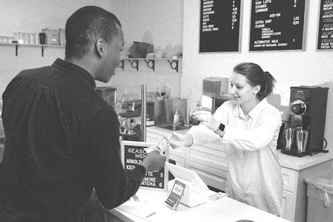 Man purchasing coffee from a cashier at a coffee shop.